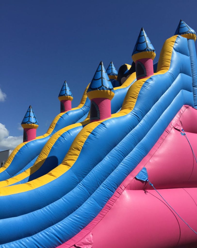 Bright inflatable slide with colorful turrets against a clear blue sky. Fun and playful atmosphere.